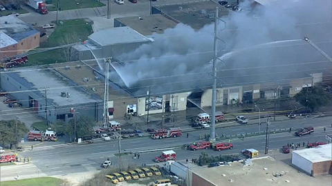 Bomberos trabajan en incendio de almacén