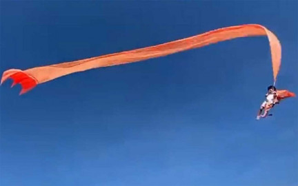 Niña es levantada en el aire por un enorme papalote