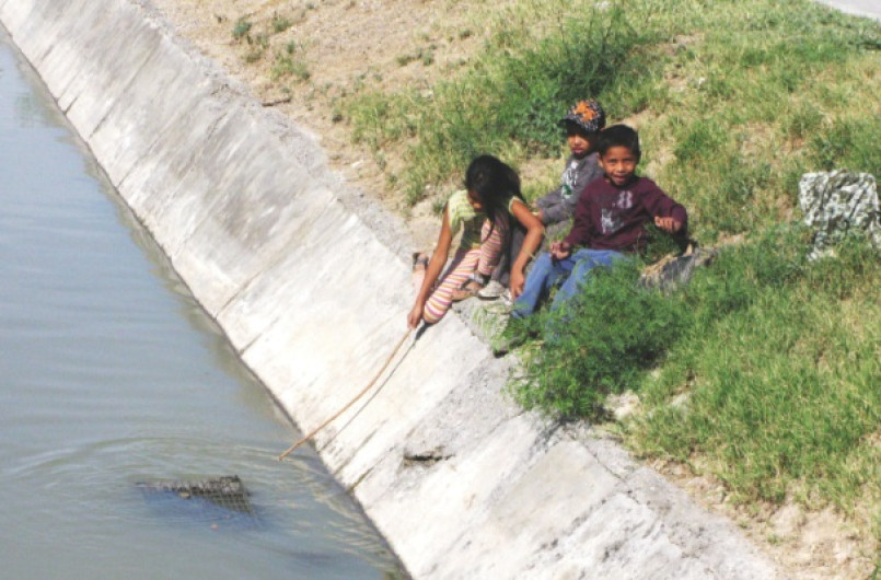 Niños juegan en canal de aguas negras